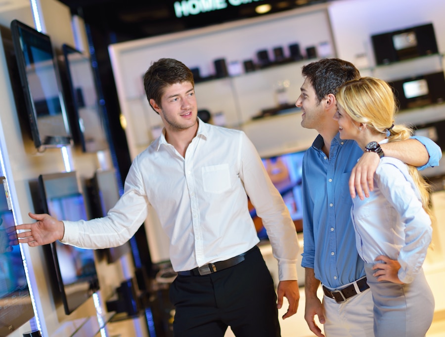 Salesperson showing a television to a shopping couple.