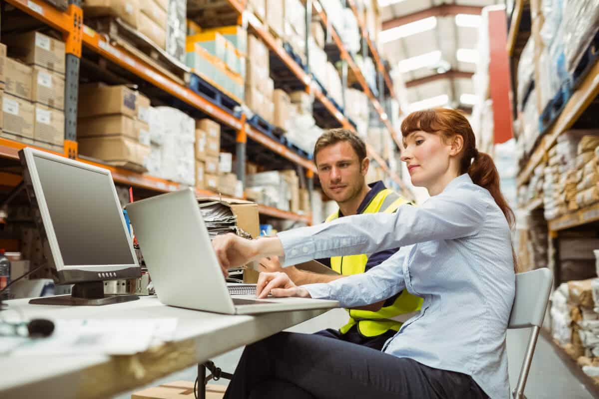 Two people in a warehouse, working together on a computer