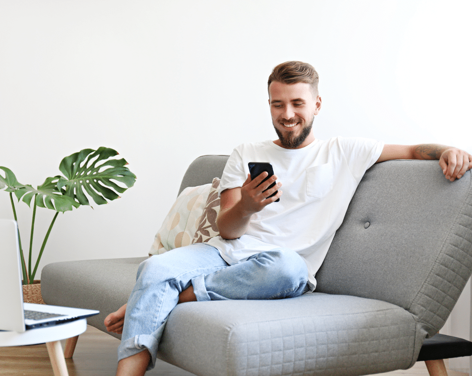 Person On Couch Looking At Mobile Phone