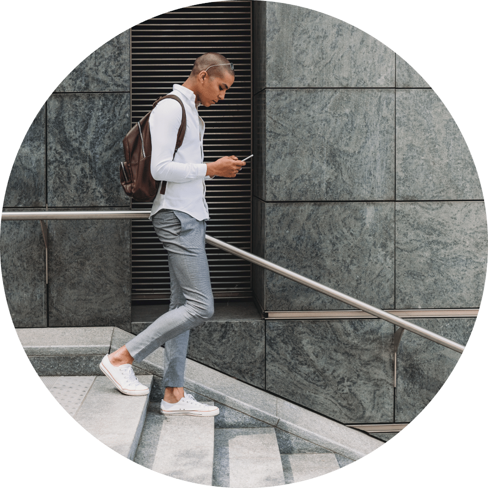 Young adult businessman in the city going down the stairs with smart phone.